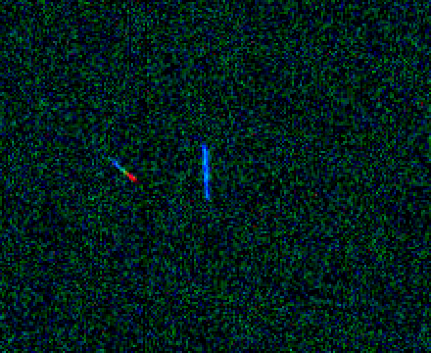Enhanced original scan crop: two cosmic-ray tracks, one running from blue to red along its length.